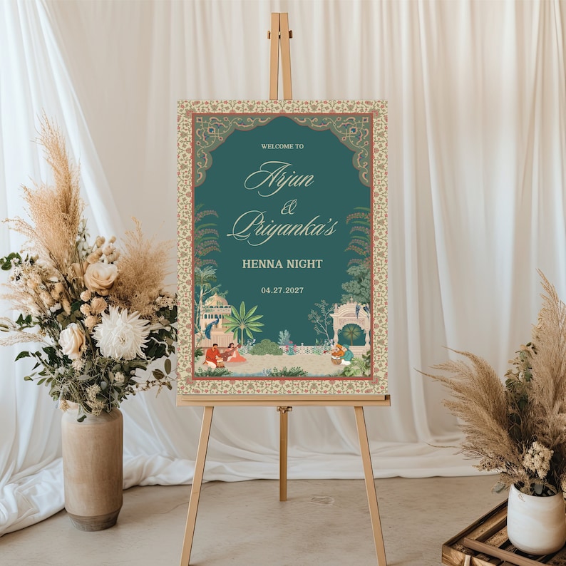 May include: A teal blue welcome sign with a gold ornate frame and a floral design. The sign reads "Welcome to Arjun & Priyanka's Henna Night 04.27.2027".