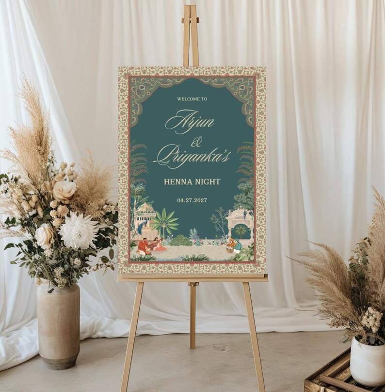 May include: A teal blue welcome sign with a gold ornate border and a floral design. The sign reads "Welcome to Arjun & Priyanka's Henna Night 04.27.2022".