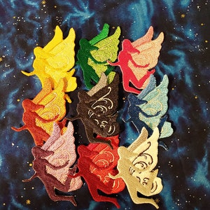 May include: A set of ten embroidered iron-on patches featuring colorful fairy silhouettes with wings. The fairies are in various poses and have different colored wings, including yellow, green, red, orange, brown, blue, pink, and cream.