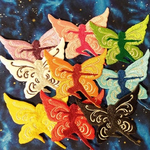 May include: A collection of embroidered butterfly patches in various colors, including pink, orange, yellow, green, and blue. Each patch features a stylized fairy figure within the butterfly wings, with intricate detailing and a celestial background.