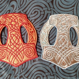 May include: Two embroidered patches depicting the Norse symbol Mjolnir, Thor's hammer. One patch is red and gold, the other is silver and gold.