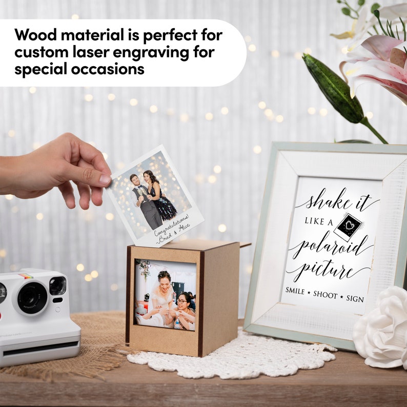 Op de afbeelding: Een houten fotodoos met een Polaroid-camera en een ingelijst bord met de tekst "shake it like a polaroid picture". Een persoon houdt een foto vast met "Gefeliciteerd Brad & Alice".