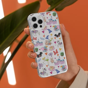 Könnte beinhalten: Eine transparente Handyhülle mit einem bunten Cartoon-Muster mit Disney-Charakteren und -Symbolen. Die Hülle hat einen weißen Hintergrund und zeigt Figuren wie Mickey Mouse, Cinderella und Tinkerbell.