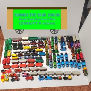 May include: A large collection of assorted wooden toy train engines and carriages in various colors including blue, red, green, yellow, and grey. A sign at the top reads THOMAS THE TANK ENGINE WOODEN TRAIN CHARACTERS & MORE (QUALITY B minus).