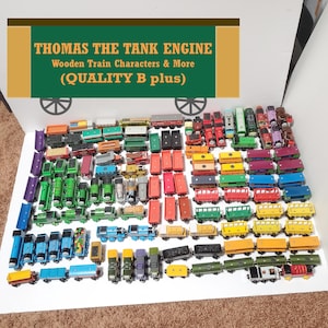 May include: A large collection of wooden toy trains and railway cars in various colors including green, blue, red, yellow, and purple. A sign at the top reads THOMAS THE TANK ENGINE Wooden Train Characters & More (QUALITY B plus).