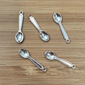 Peut inclure: Cinq breloques en forme de cuillère en argent, chacune avec un bol arrondi et une boucle en haut pour l'attacher à un collier ou un bracelet.