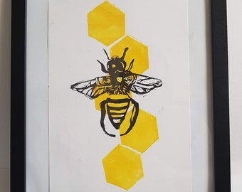Puede incluir: Una impresión enmarcada en blanco y negro de una abeja con panal de abeja amarillo detrás.