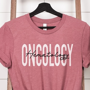 May include: A pink t-shirt with the text "ONCOLOGY Hematology" in white lettering with a black outline.