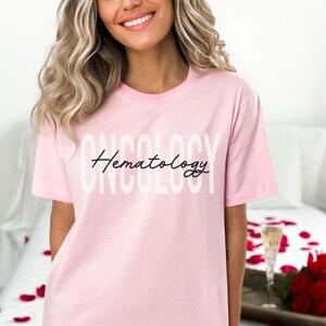 May include: A pink t-shirt with the text "Oncology" in white and "Hematology" in black cursive writing.