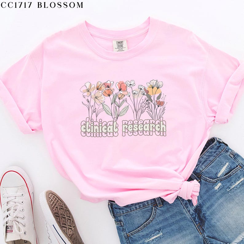 May include: Pink t-shirt with a floral design and the text "clinical research" in a retro font.
