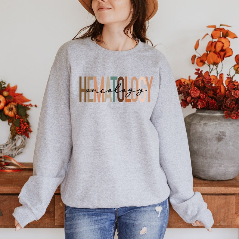 May include: A gray sweatshirt with the text "HEMATOLOGY oncology" in colorful letters. The letters are in shades of brown, orange, and green.