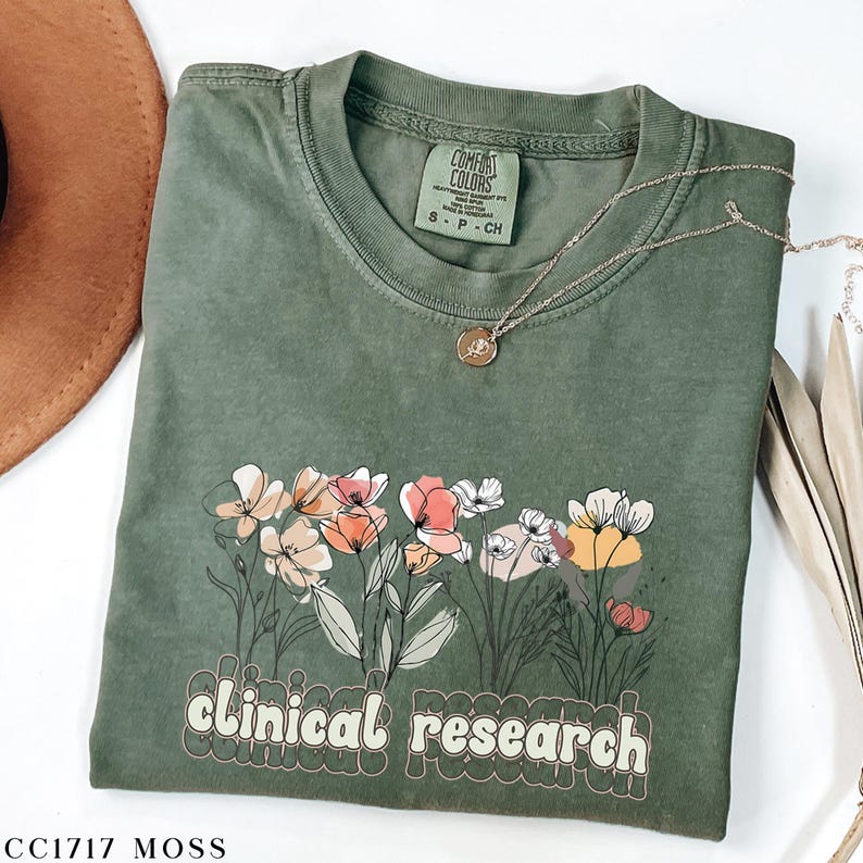 May include: A green t-shirt with a floral design and the text "clinical research" in a retro font. The shirt is made of a soft, comfortable material and is perfect for everyday wear.