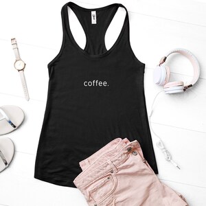 Puede incluir: Camiseta negra de tirantes con el texto "coffee." impreso en blanco en la parte delantera. La camiseta est&aacute; sobre una superficie blanca con unos pantalones cortos de mezclilla rosa, un reloj y unos auriculares.