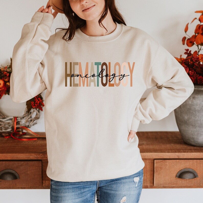 May include: A beige sweatshirt with the text "HEMATOLOGY oncology" printed in colorful letters.