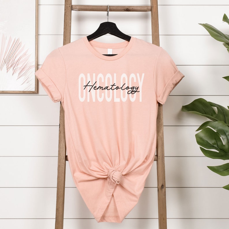 May include: A peach-colored t-shirt with the text "ONCOLOGY Hematology" printed in white on the front.
