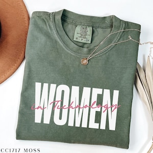 May include: A green t-shirt with the text "WOMEN in Technology" in white and pink lettering. The shirt is made of a soft, comfortable material and has a relaxed fit.