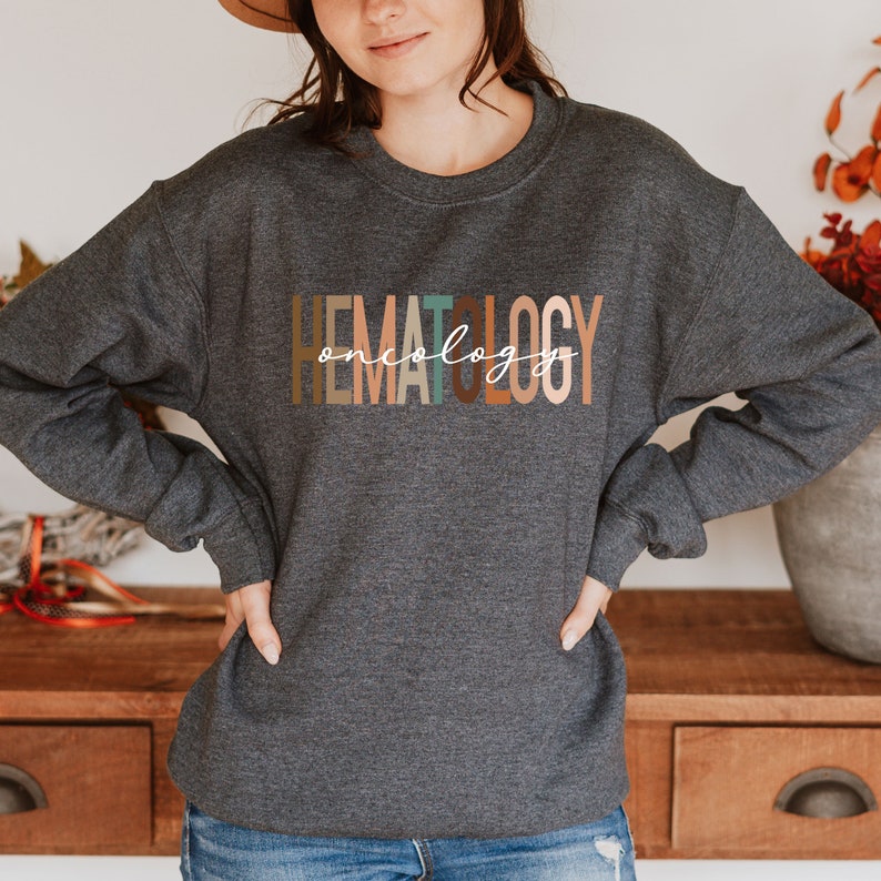 May include: A dark gray sweatshirt with the text "HEMATOLOGY oncology" printed in colorful letters. The letters are in different shades of brown, orange, and green.