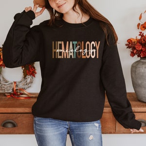 May include: Black sweatshirt with the text "HEMATOLOGY oncology" in colorful letters.