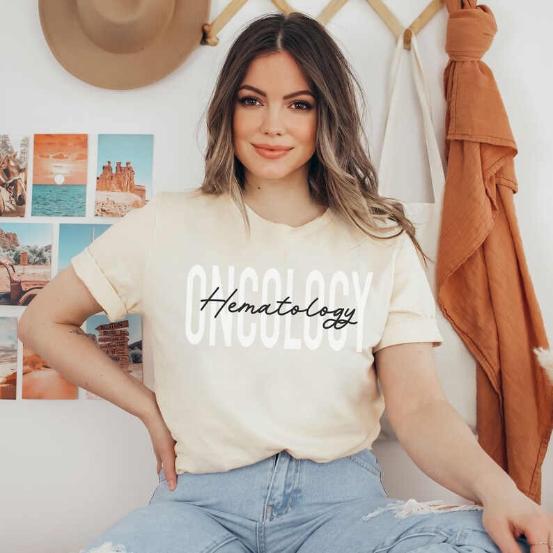 May include: A woman wearing a light yellow t-shirt with the text "Oncology Hematology" in white and black lettering.