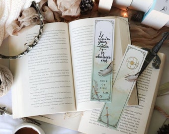 May include: A flat lay featuring a white sweater, a book with a bookmark that reads "I claim your soul to whatever end", a candle, a sword, a cup of coffee, and a spool of twine.