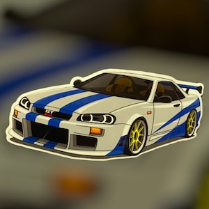 Puede incluir: Un Nissan Skyline GT-R blanco con rayas de carreras azules y llantas amarillas. El coche es un modelo popular de la franquicia de películas Fast and Furious.