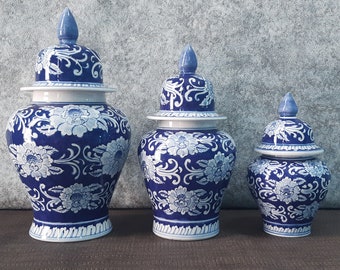 May include: Three blue and white porcelain ginger jars with floral designs. The jars are of varying sizes and have lids.