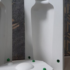 May include: Two white plaster molds for making a bottle. The molds are open on one side and have a round base. The molds have green plastic plugs in the sides.