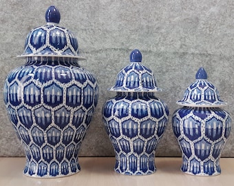 May include: Three blue and white ceramic ginger jars with a geometric pattern. The jars are of different sizes and are arranged in a row from largest to smallest.