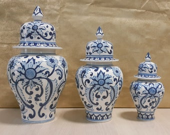 May include: Three blue and white porcelain ginger jars with floral designs. The jars are of varying sizes and have lids.