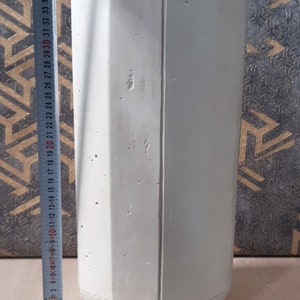 May include: A white concrete planter with an octagonal shape and a smooth, textured surface. The planter is approximately 37 inches tall.