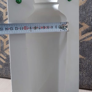 May include: White plaster mold for making a vase. The mold is 15 inches tall and has a round opening at the top. There are four green plastic stoppers on the mold.
