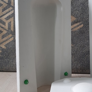 May include: White plaster mold for making a bottle or vase. The mold has a smooth, rounded interior and a textured exterior. There are five green dots on the mold.