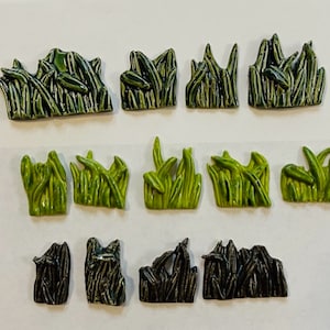 May include: A set of 12 ceramic miniature grass tiles in shades of green and gray. The tiles are designed to be used in model railroading or other miniature scenes.