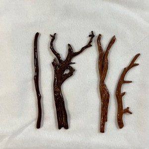 May include: Five different brown wooden branches with various shapes and sizes. The branches are arranged horizontally on a white background.