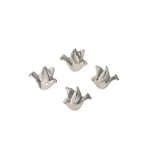 May include: Four silver ceramic doves in flight. The doves are in a white background.