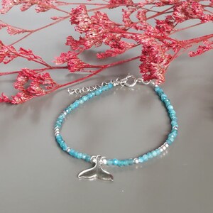 Peut inclure: Un bracelet en pierres bleues avec un pendentif en argent en forme de queue de baleine. Le bracelet est composé de petites perles rondes et possède un fermoir en argent.