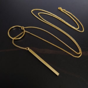 May include: A gold chain necklace with a circle pendant and a long, thin bar pendant.