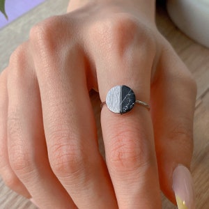 Könnte beinhalten: Ein silberner Ring mit einem schwarzen und weißen Halbkreis-Stein. Der Stein ist eine Mischung aus schwarzem und weißem Marmor.