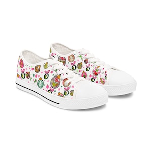 May include: White canvas low-top sneakers with a Christmas-themed print featuring cartoon characters and ornaments in pink, green, and red.