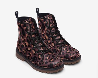 Pode incluir: Um par de botas de cano curto com estampa de leopardo em tons de castanho, preto e bege. As botas têm atacadores pretos, uma presilha na parte de trás e sola castanha escura. Calçado moderno.
