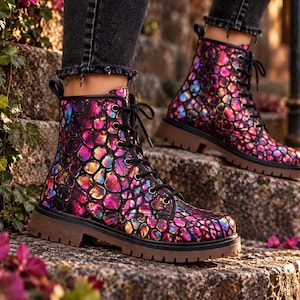 May include: Ankle-high lace-up boots featuring a vibrant, iridescent, multi-coloured scale pattern in shades of pink, purple, and gold. The boots have black laces, black metal eyelets, a pull tab at the heel, and a thick, brown, lugged rubber sole.
