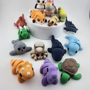 May include: A collection of 14 small, colourful, animal figurines made of polymer clay. The figurines include a penguin, unicorn, fox, turtle, octopus, seal, whale, and more.