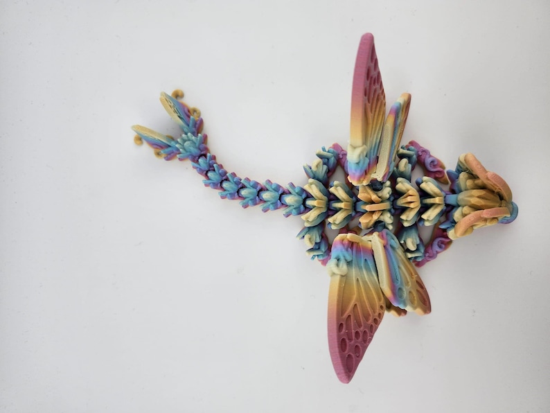 May include: A multi-colored 3D printed dragon figurine with wings, a tail, and a head. The dragon is made of plastic and has a rainbow color scheme.