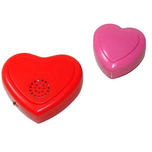 Pode incluir: Duas caixas de som em forma de coração, uma vermelha e outra rosa. O coração vermelho tem um alto-falante na frente.