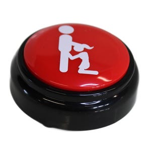 May include: A novelty button with a red top and black base. The red button features a white graphic of two figures in a suggestive pose. The button is round and appears to be made of plastic.
