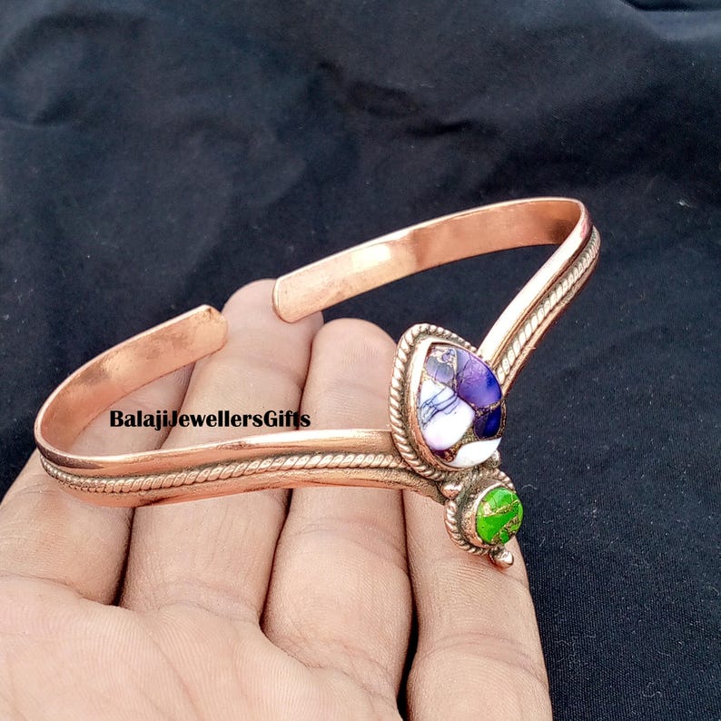 Op de afbeelding: Koperen manchetarmband met een druppelvormige paarse en witte steen en een kleine groene steen. De armband heeft een textuurontwerp en de tekst "BalajiJewellersGifts".