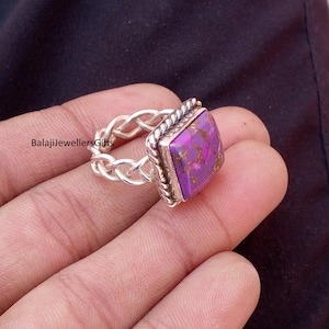 Puede incluir: Anillo de plata con una piedra preciosa cuadrada de color púrpura. La piedra tiene motas doradas y está engastada en un marco plateado con un diseño de cuerda trenzada. El texto "BalajiJewellersGifts" es visible.