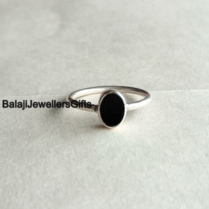 May include: A silver ring with a black oval gemstone.