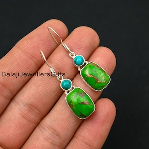 May include: A pair of silver dangle earrings featuring green and blue turquoise stones. The earrings are rectangular in shape and have a smaller round turquoise stone as an accent.