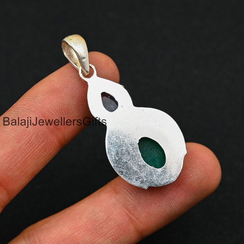 May include: Silver pendant with two green gemstones set in a silver frame. The pendant has a bail for attaching to a chain.